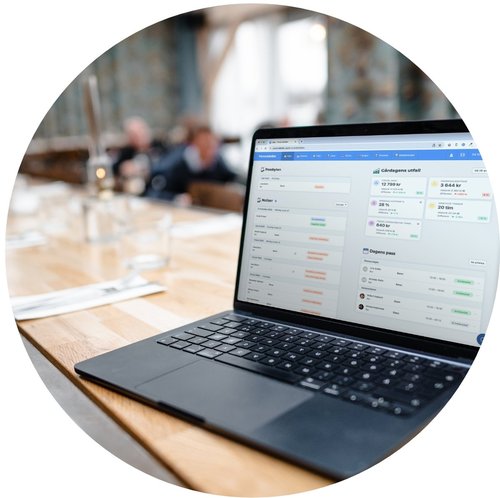 Ein Laptop mit dem Dashboard von HeyCrew steht auf einem Restauranttisch in heller Umgebung.