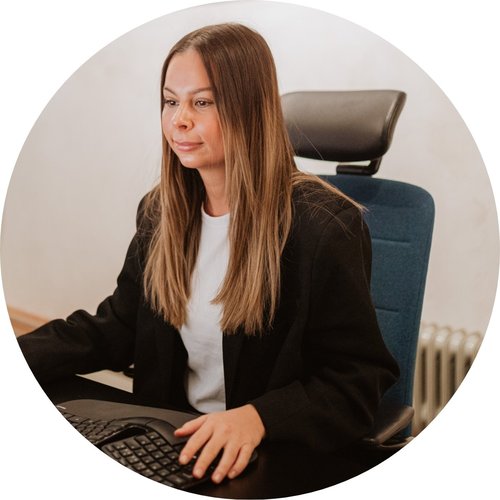 Eine Frau mit Headset sitzt an einem Bürotisch.